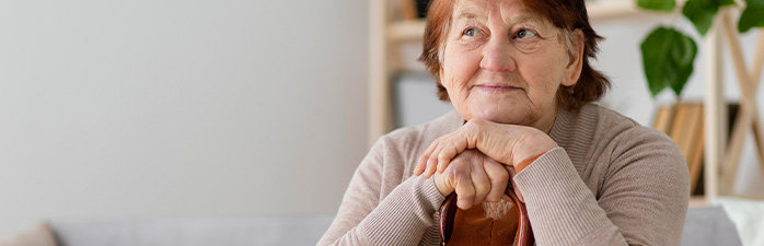 Woman sitting her cane under her chin